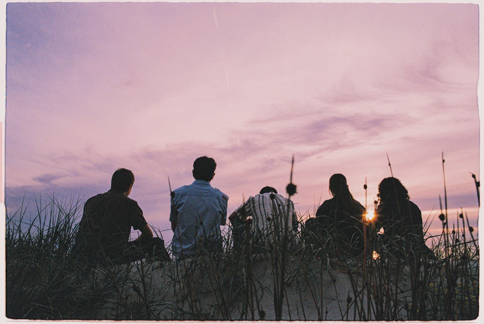 South Coast band members watching the sunset from beach grass