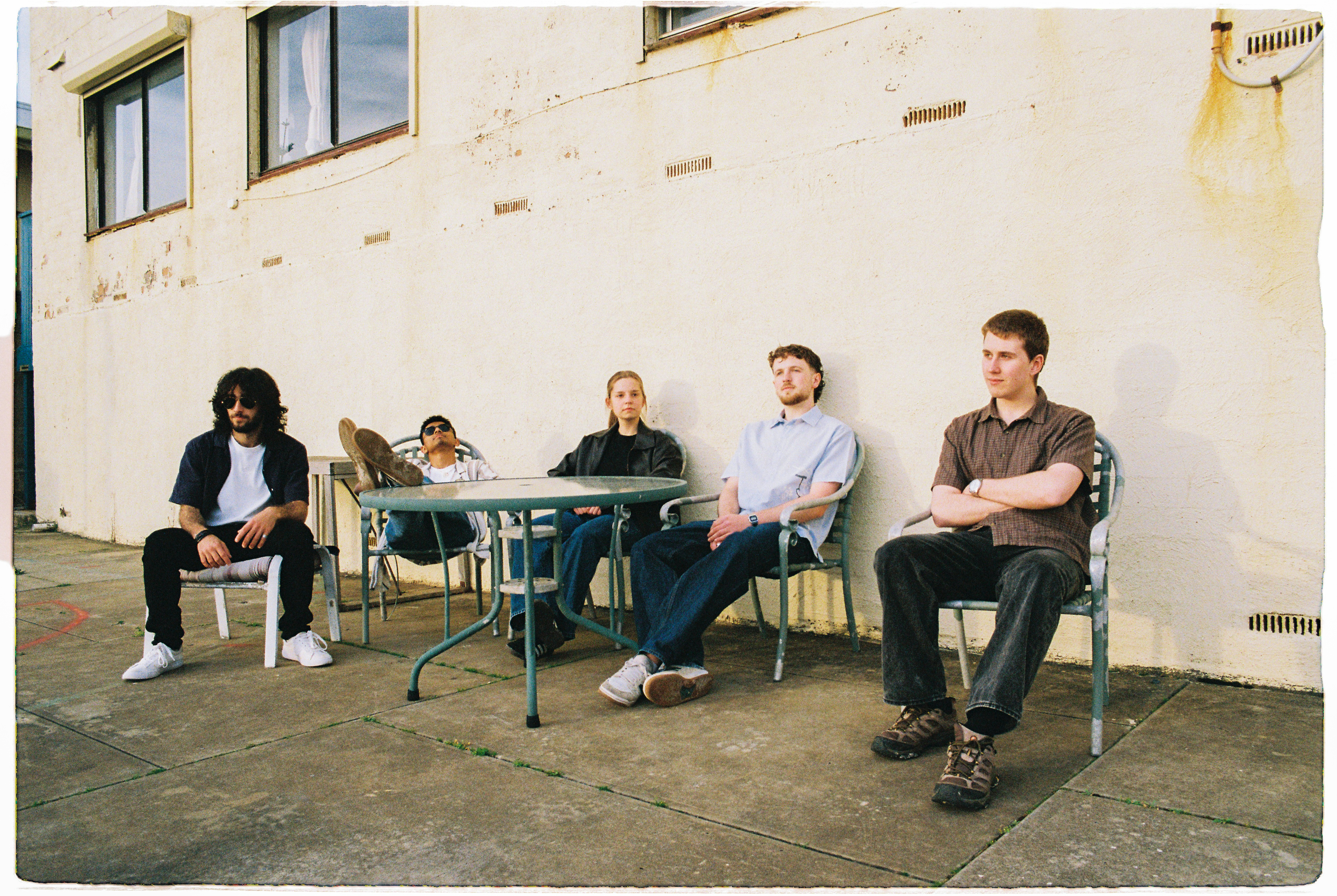 South Coast band members seated outside against a cream wall